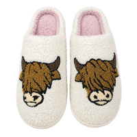 Pair of white slippers with highland cow designs on a white background